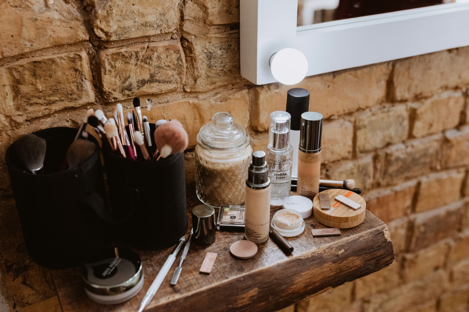 Postazione trucco con fondotinta fluido, siero, ciprie e pennelli davanti allo specchio