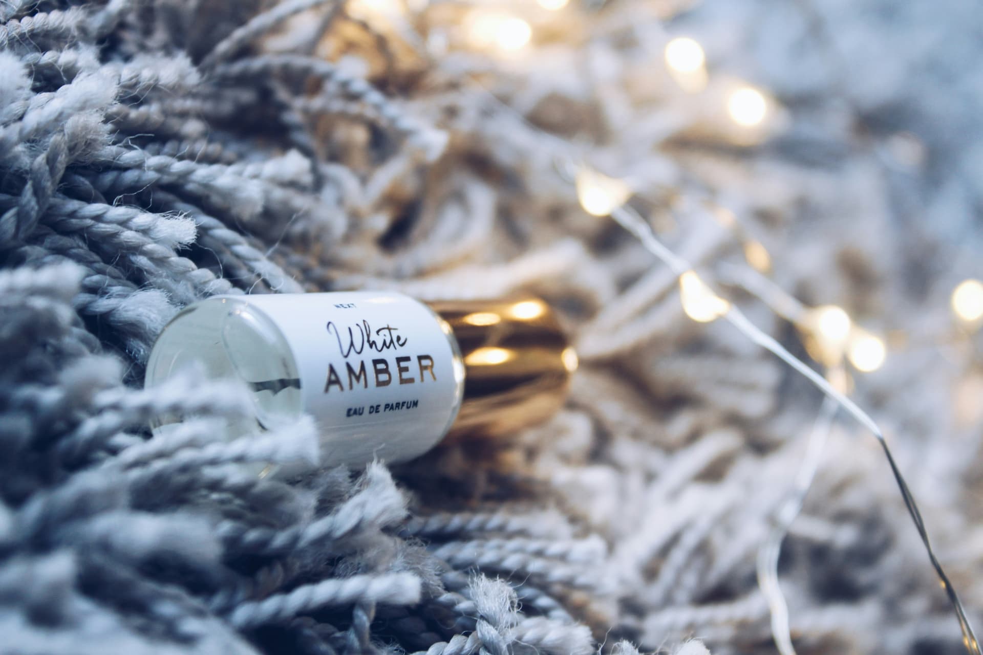 Profumi all'ambra: flacone White Amber tra lana e luci calde