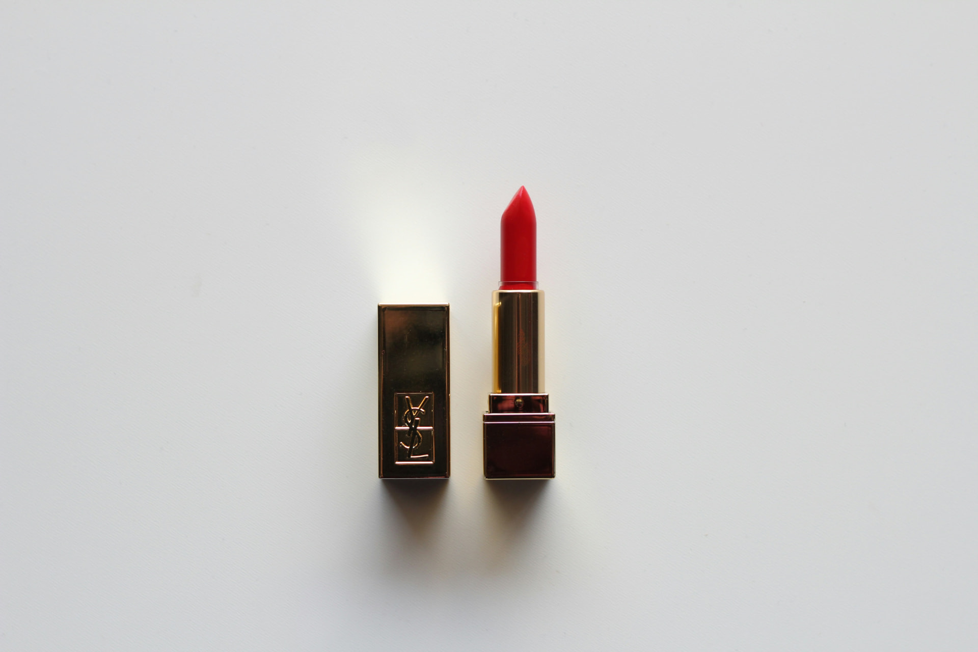 Rossetto rosso iconico con astuccio dorato aperto su fondo bianco
