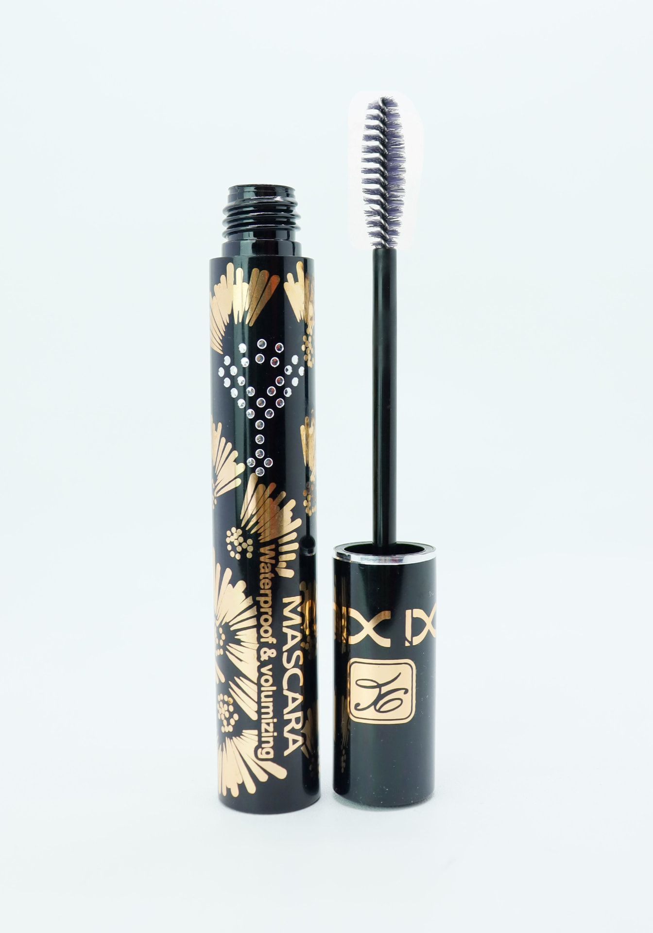 Mascara volumizzante waterproof nero e oro con scovolino estratto su fondo bianco
