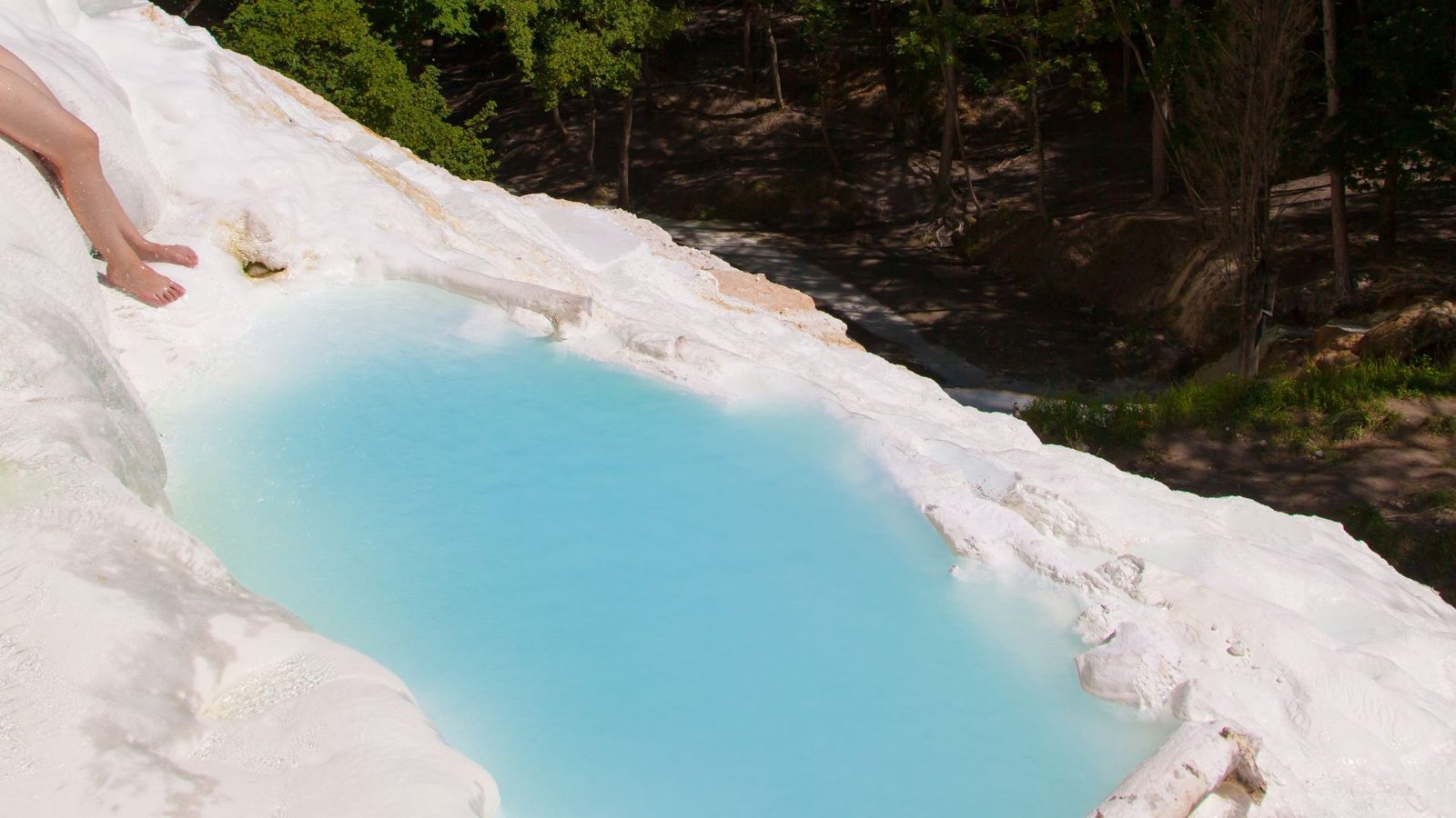 Pozza di acqua termale turchese tra rocce bianche