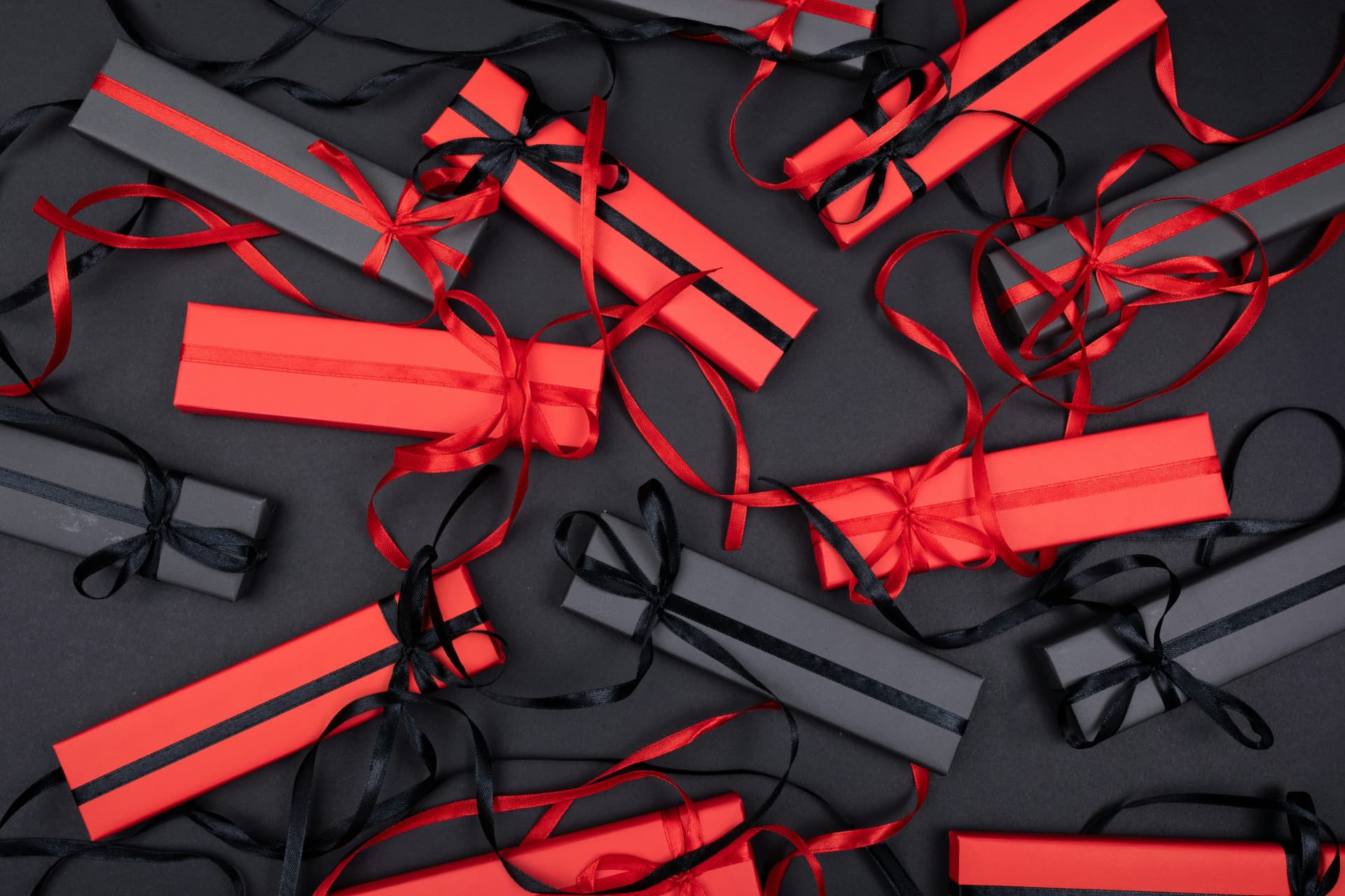 Confezioni regalo rosse e nere con nastri di raso su sfondo scuro