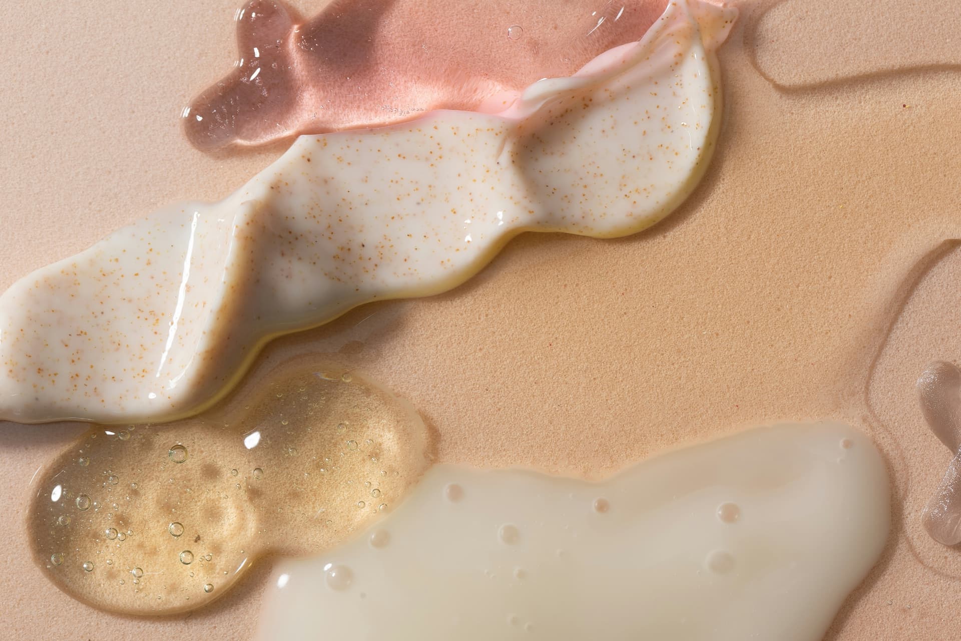 Texture di creme e sieri su fondo rosa cipria