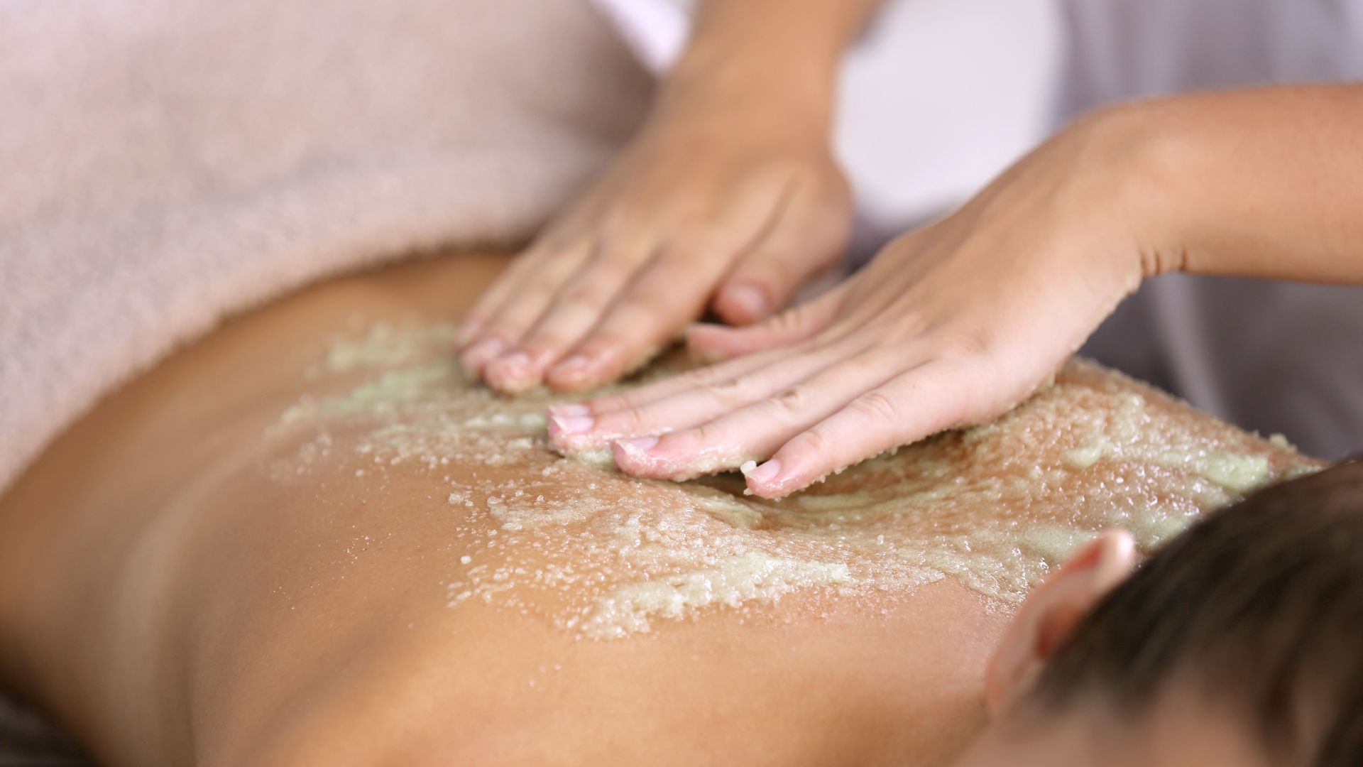Scrub esfoliante corpo massaggiato sulla schiena in spa
