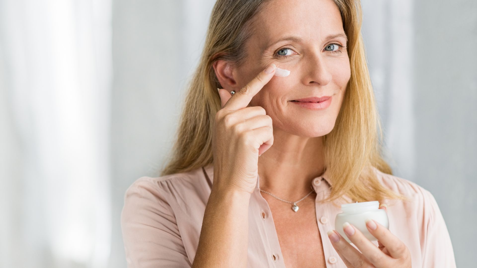 Donna matura che applica la crema viso sul volto