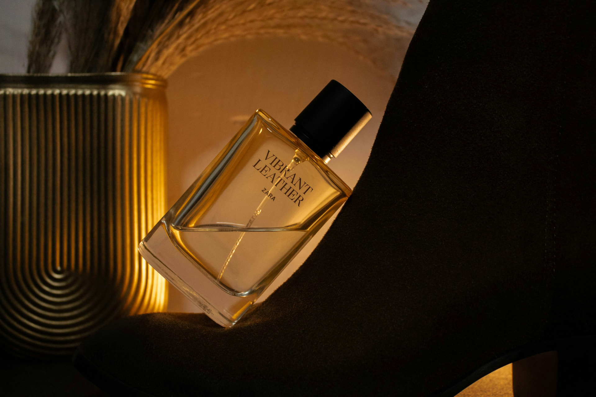 Flacone di profumo ambrato in controluce appoggiato su tessuto scamosciato scuro