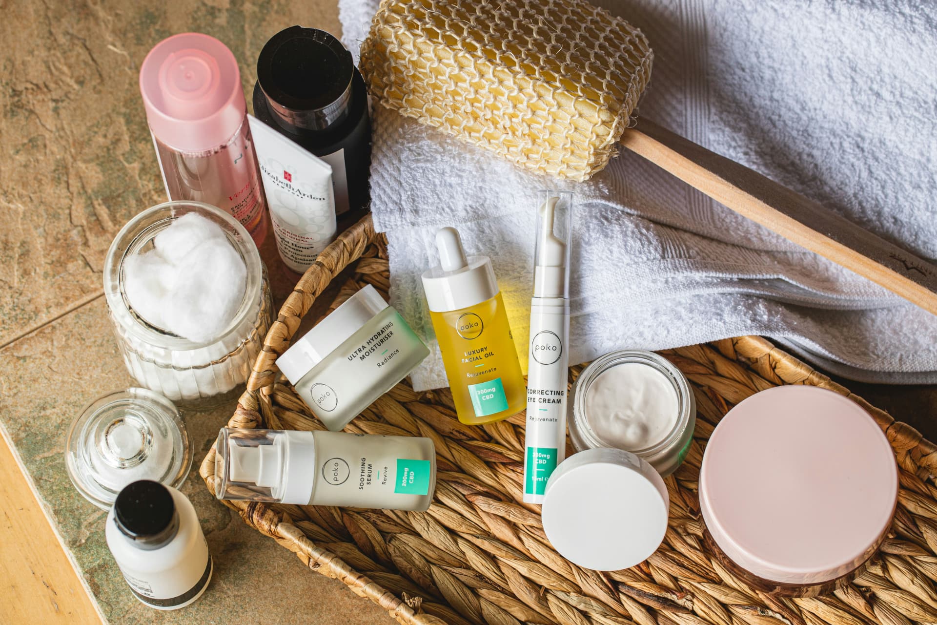 Routine skincare con acqua micellare, detergente, siero, olio viso e crema in un cesto