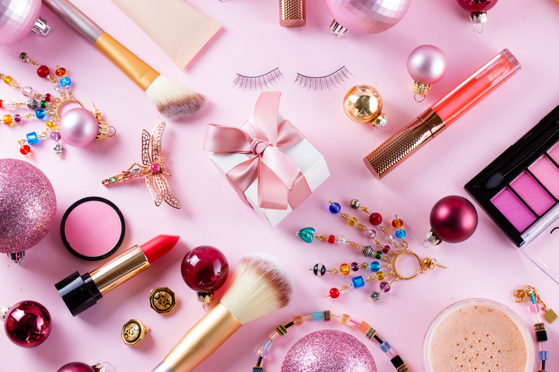 Prodotti make-up con decorazioni natalizie su fondo rosa