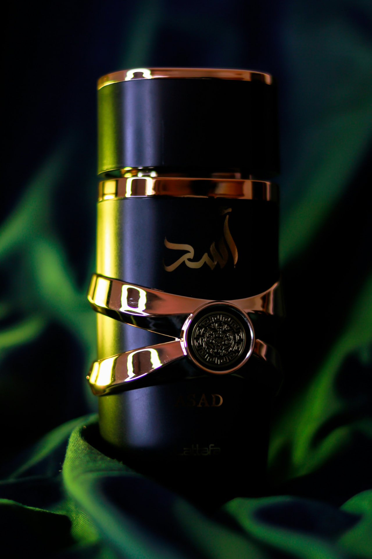 Flacone di profumo arabo nero e oro su tessuto verde