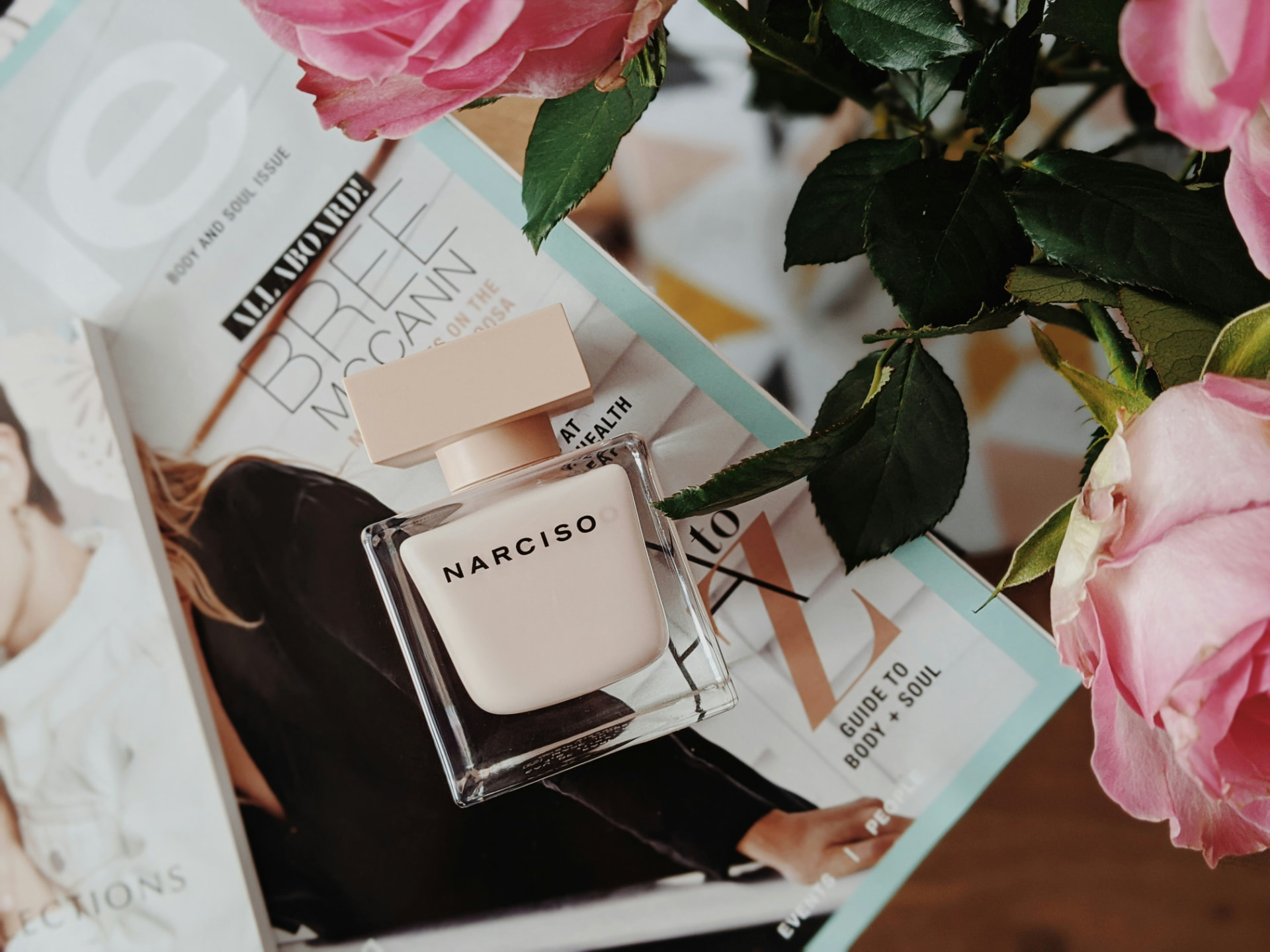 Flacone rosa cipria Narciso Rodriguez su riviste con rose rosa