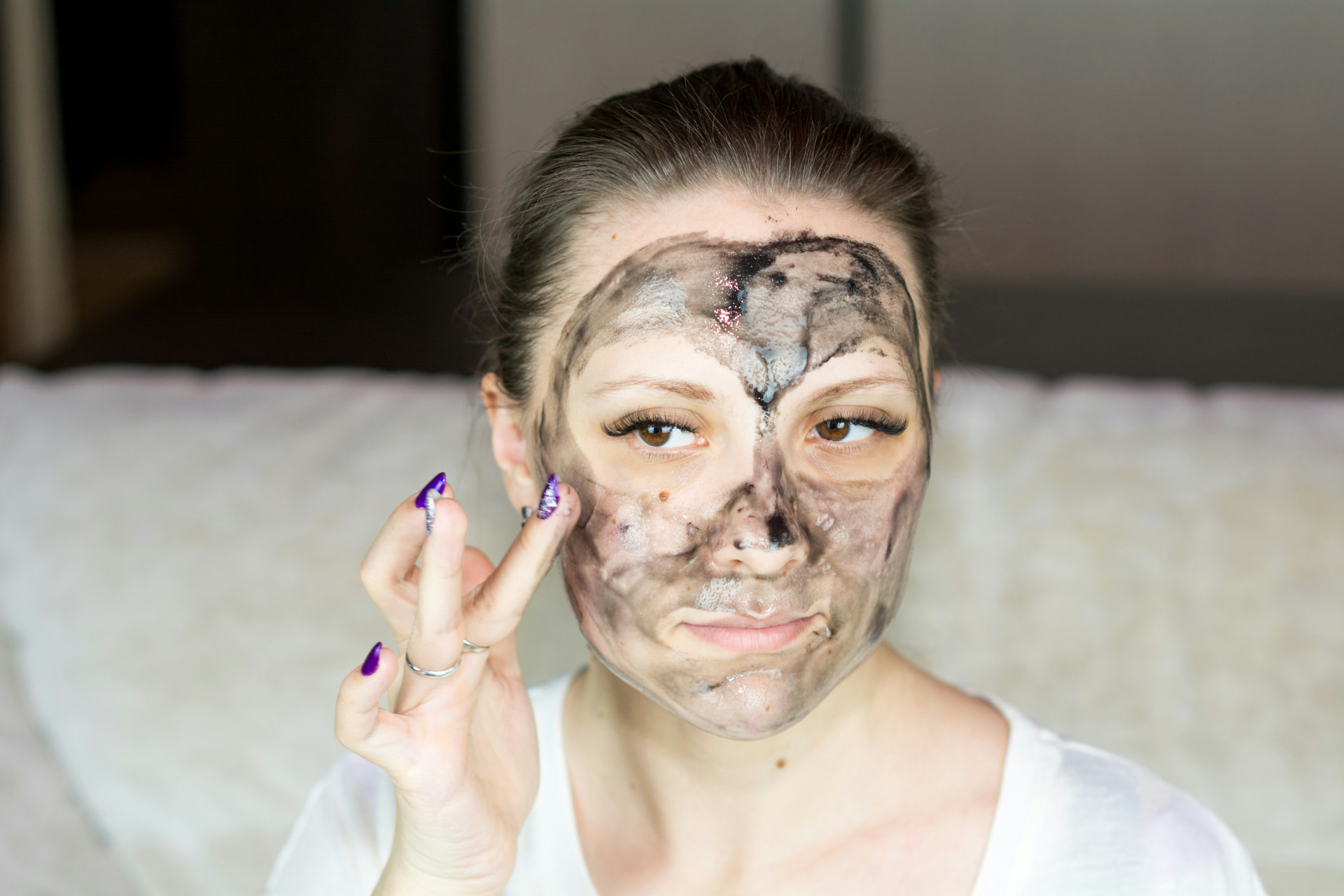 Ragazza applica una maschera viso al carbone nera durante la skincare routine