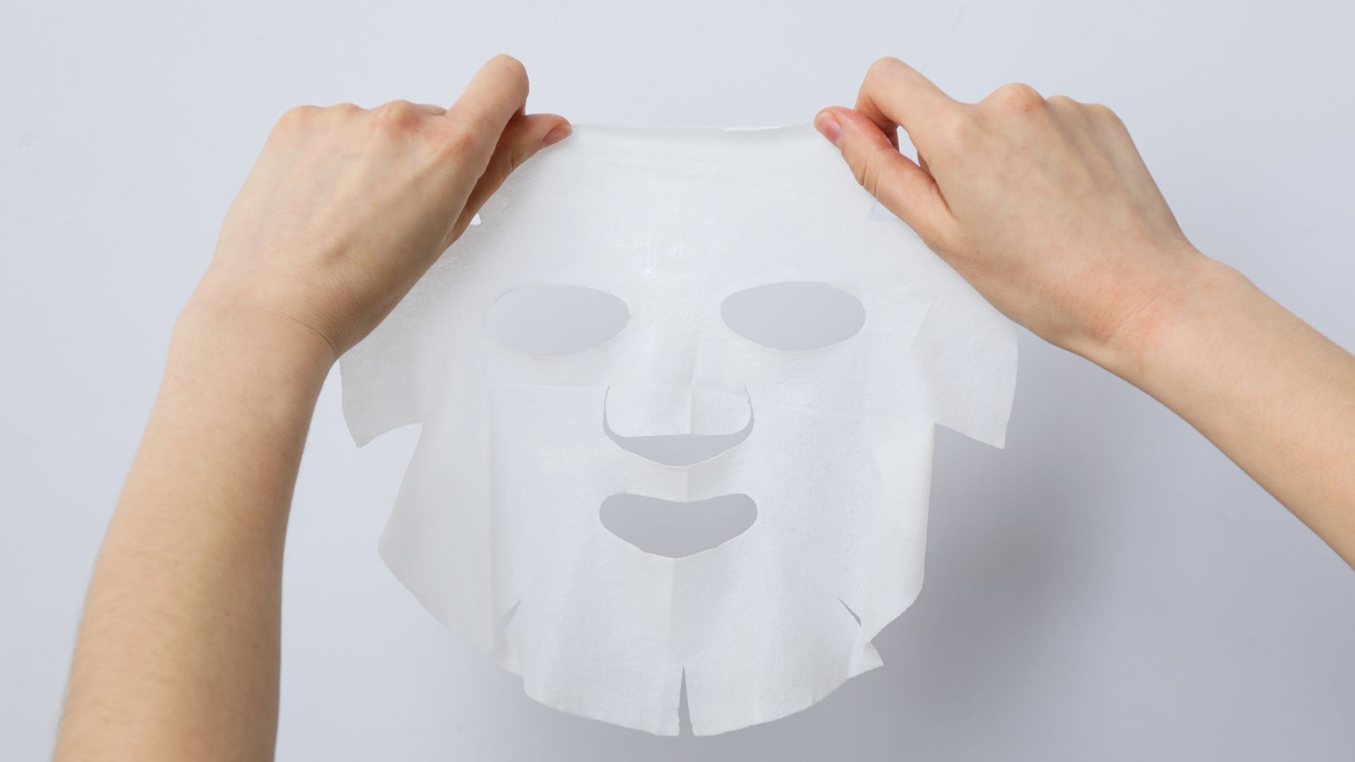 Mani che aprono una maschera viso in tessuto