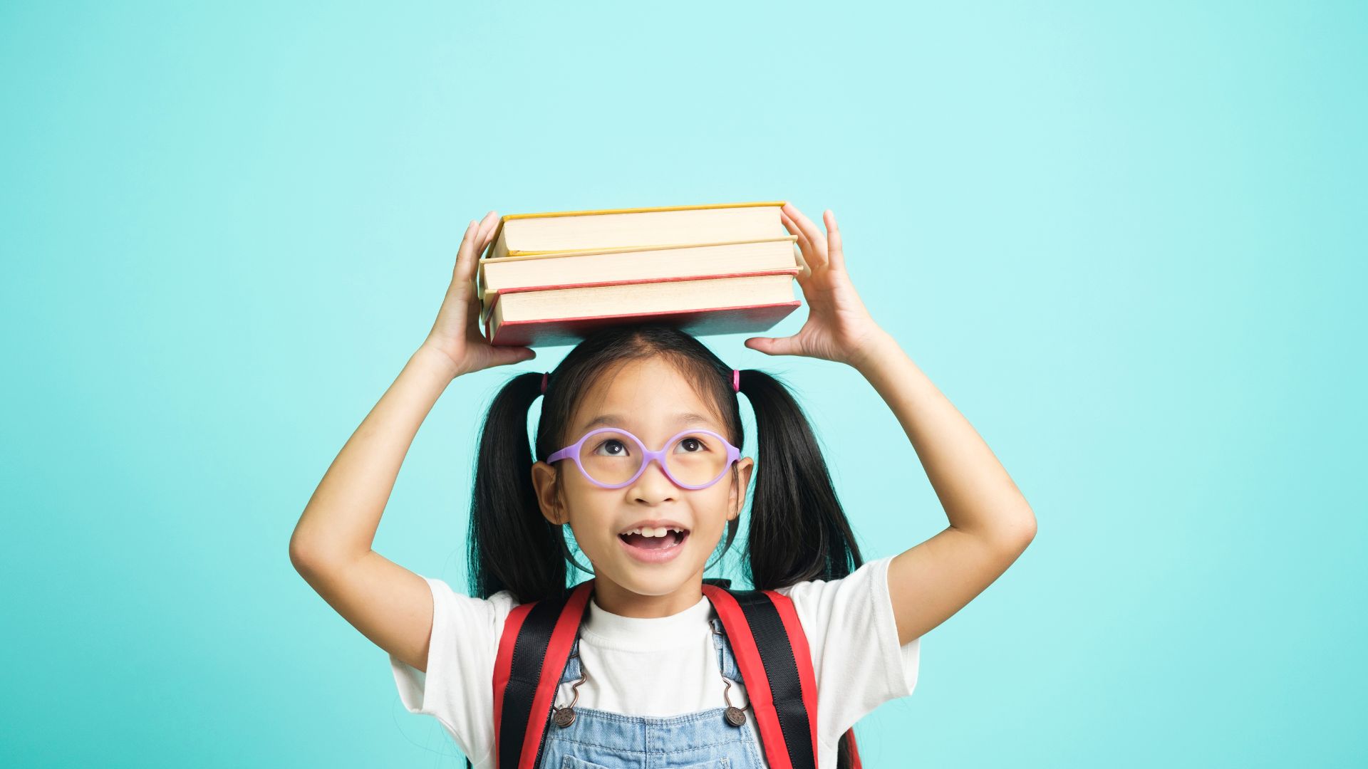 Bambina sorridente con i libri in testa