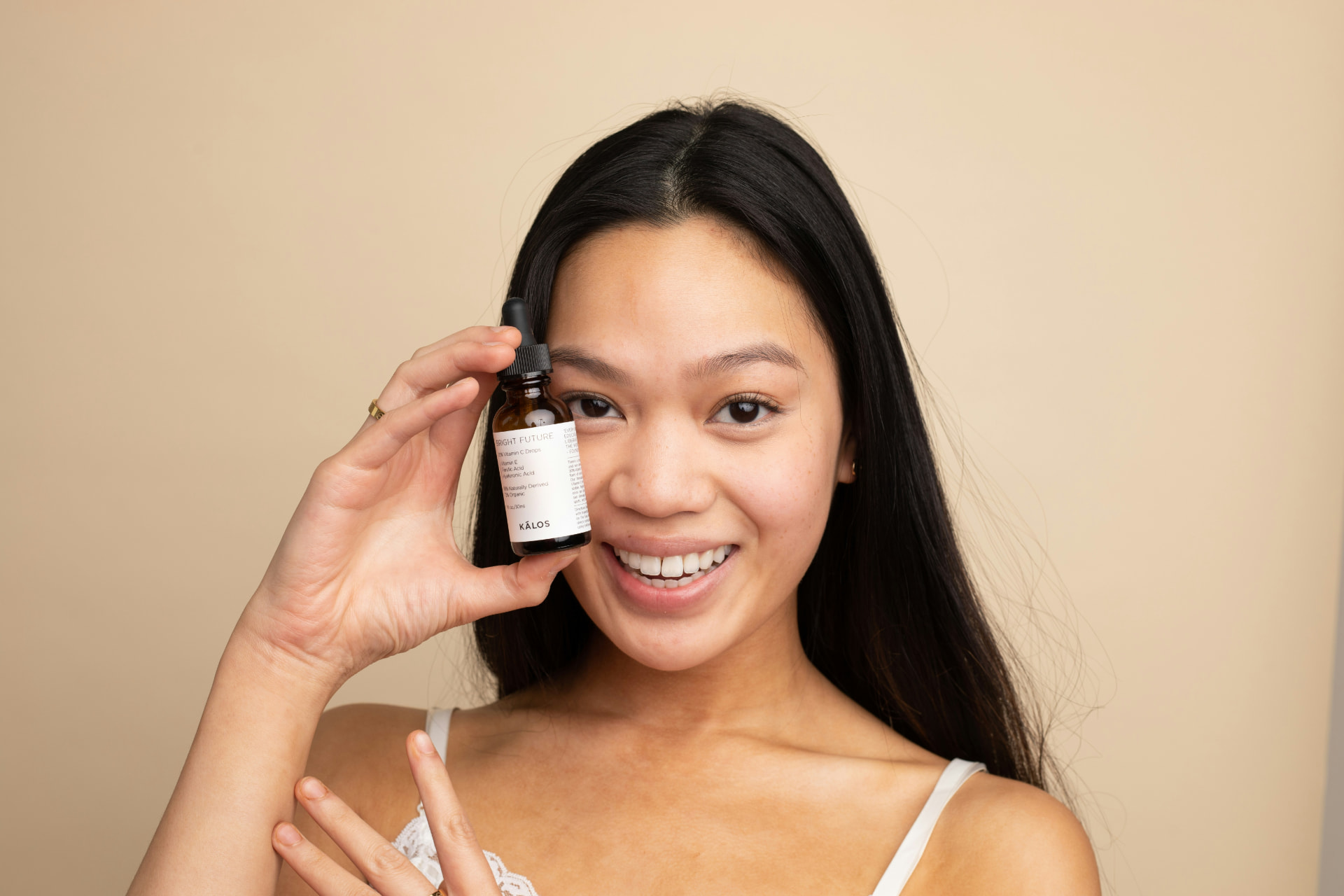 Ragazza sorridente mostra un flacone contagocce di siero viso alla vitamina C