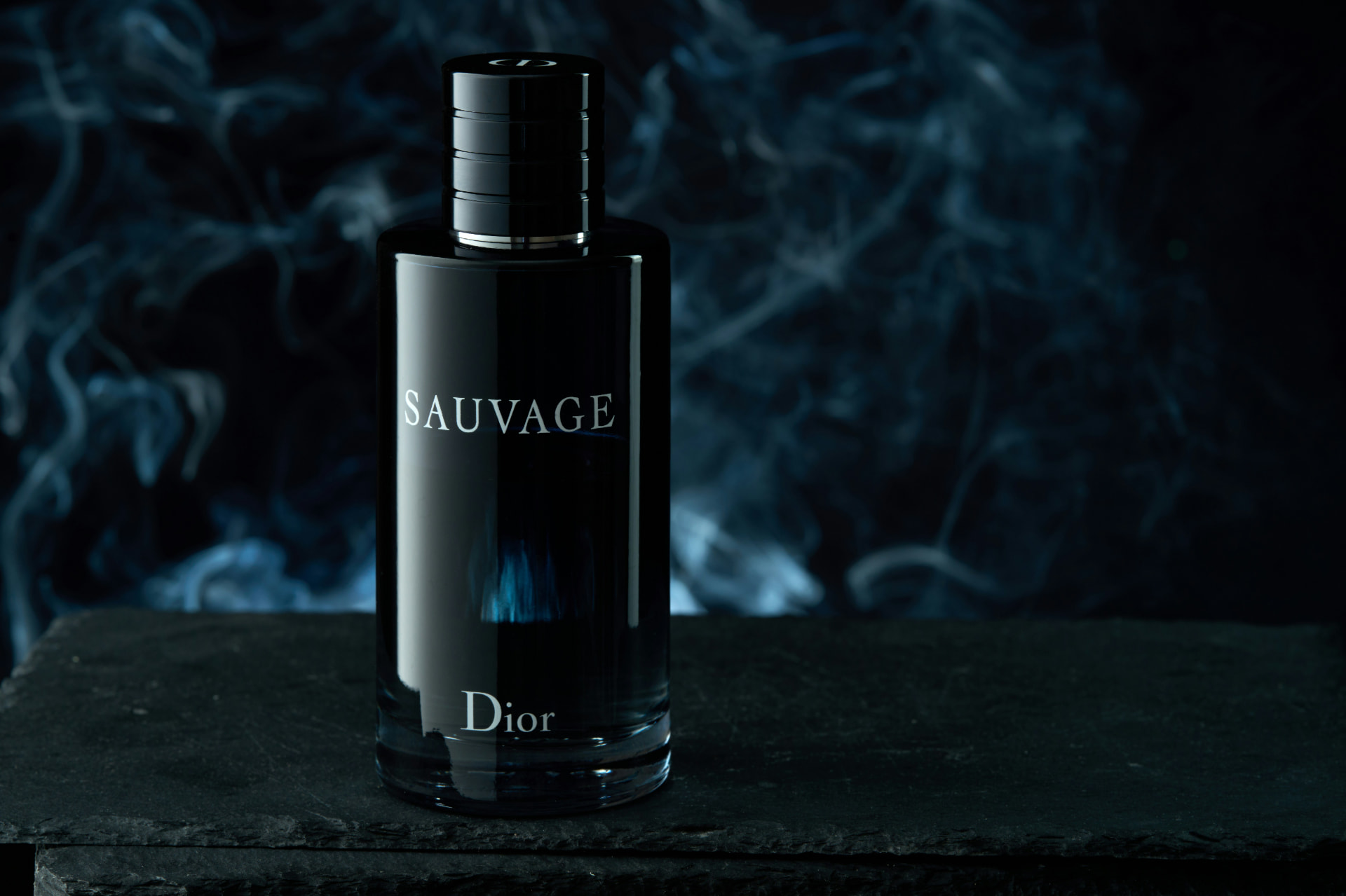 Flacone Dior Sauvage blu scuro su pietra con fumo sullo sfondo