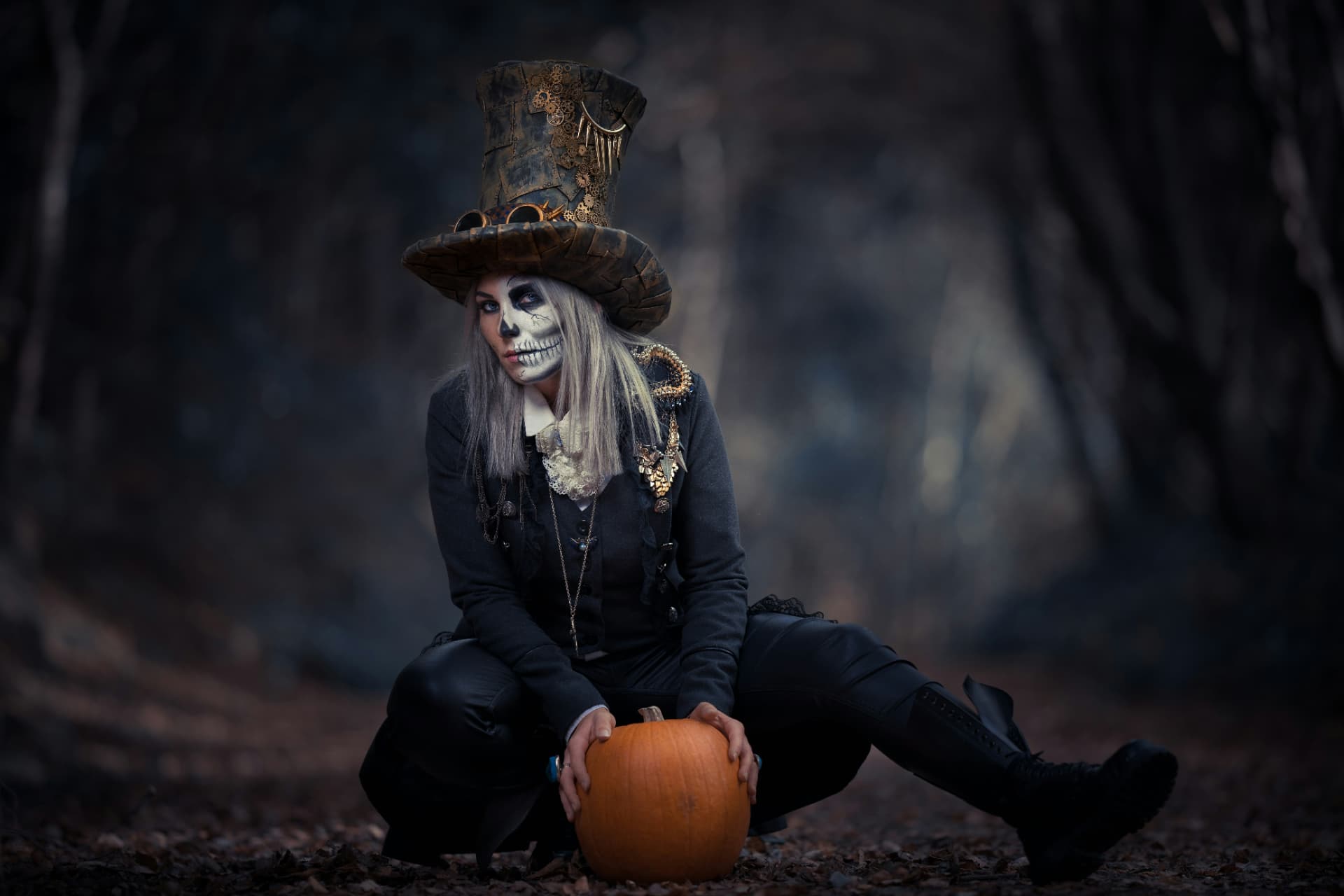 Trucco Halloween da scheletro con cappello scuro e zucca in un bosco