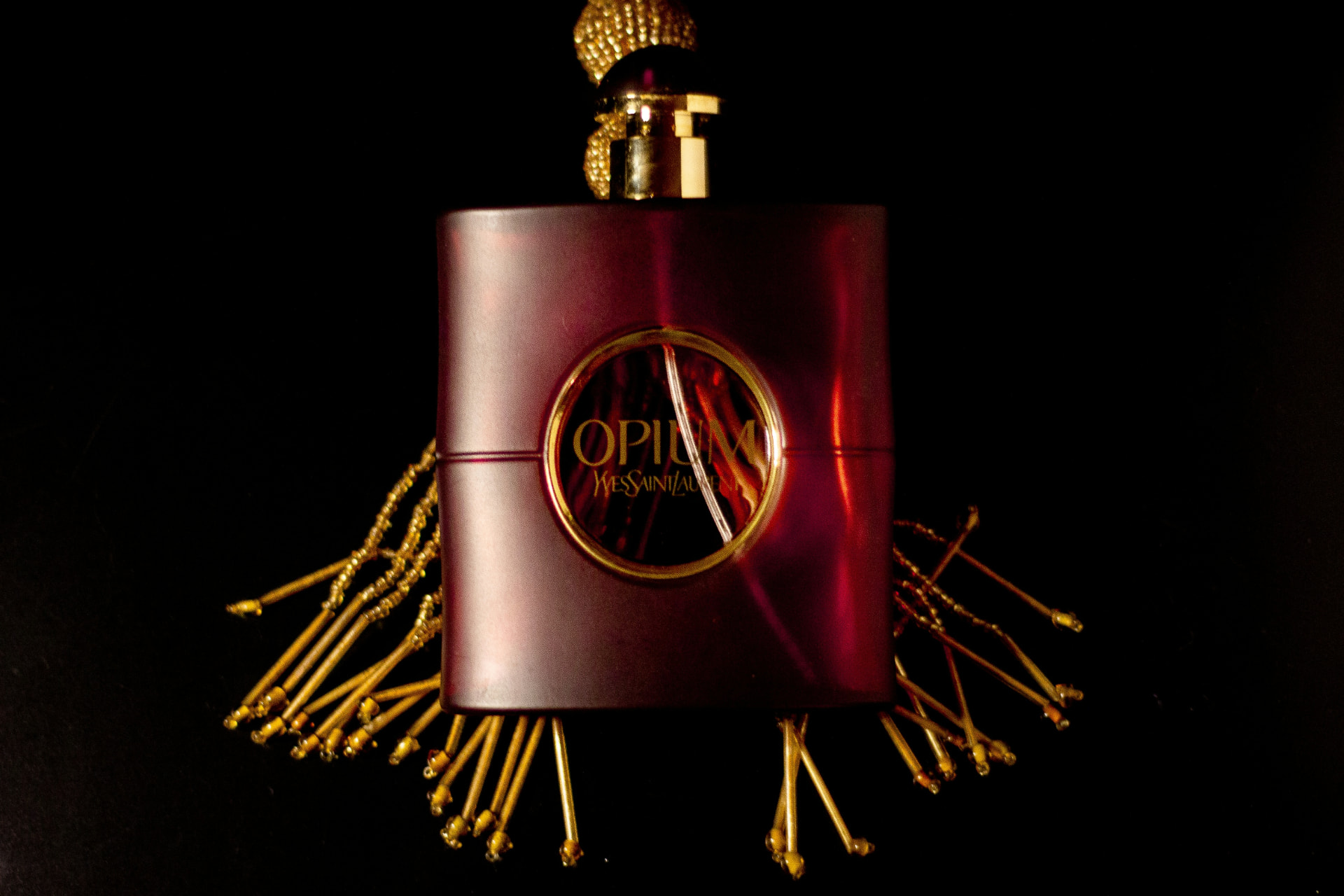 Flacone Yves Saint Laurent Opium con nappa dorata su fondo nero