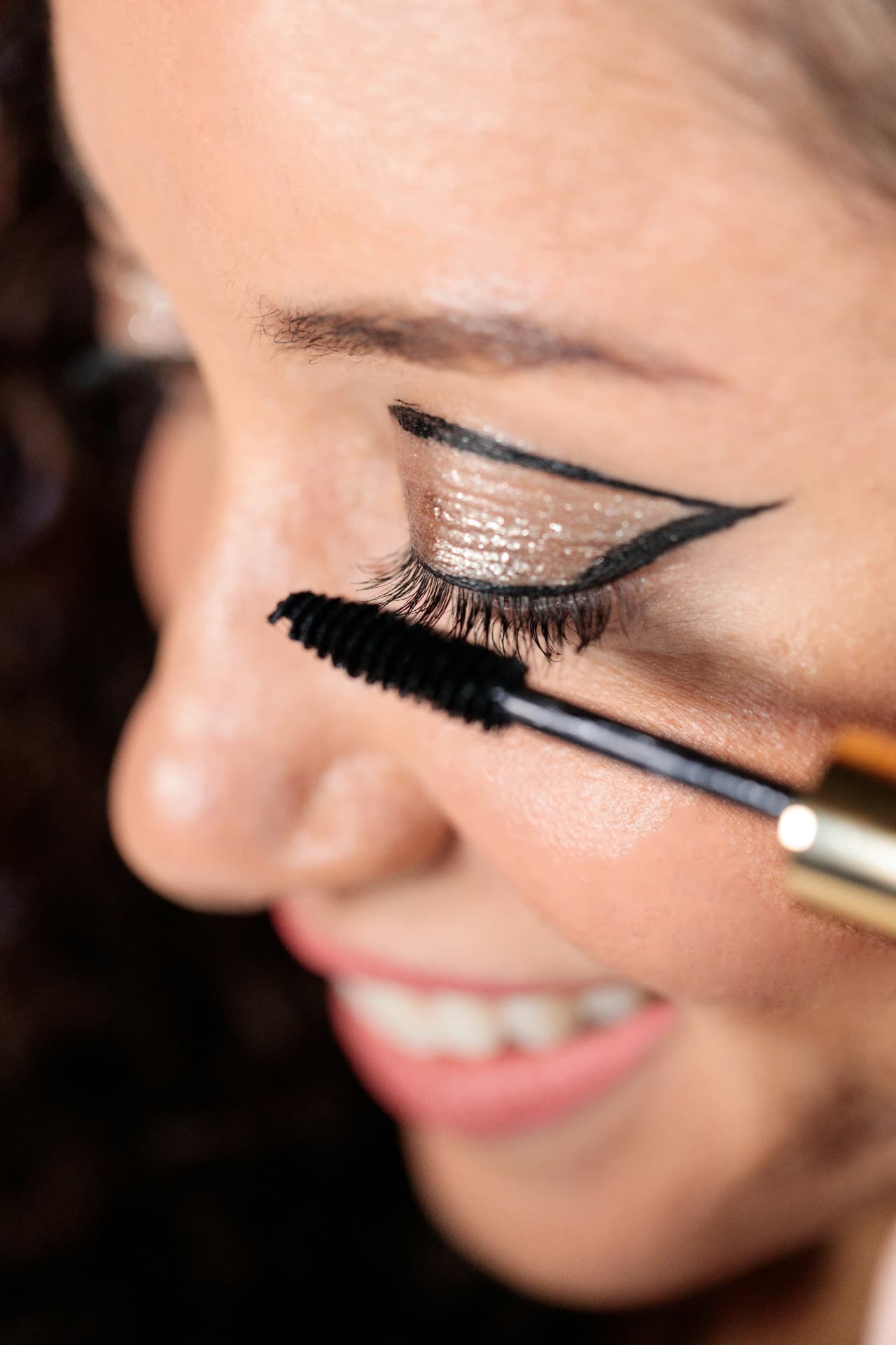 Applicazione del mascara con scovolino sulle ciglia superiori in primo piano