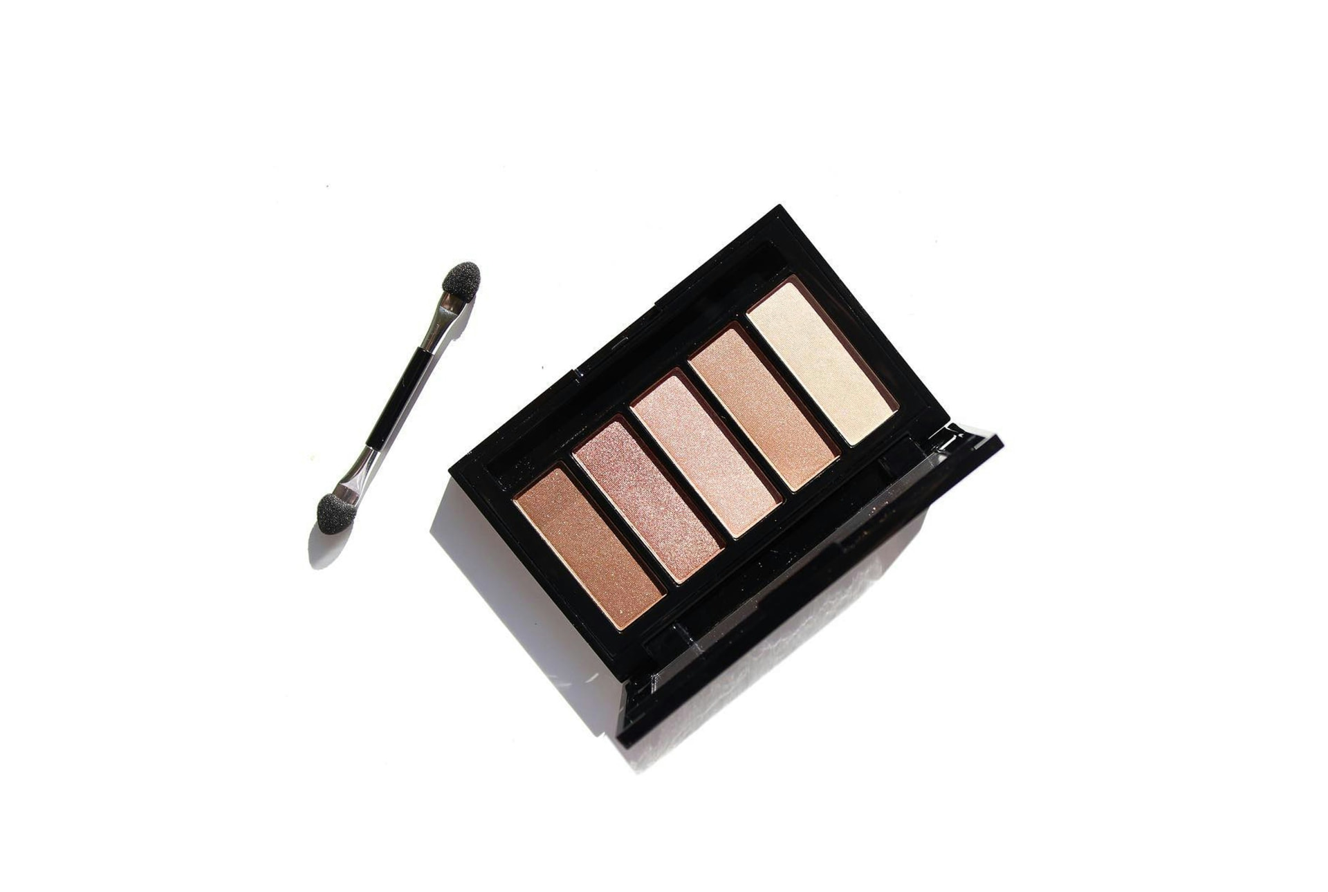 Palette compatta di cinque ombretti perlati con applicatore su fondo bianco
