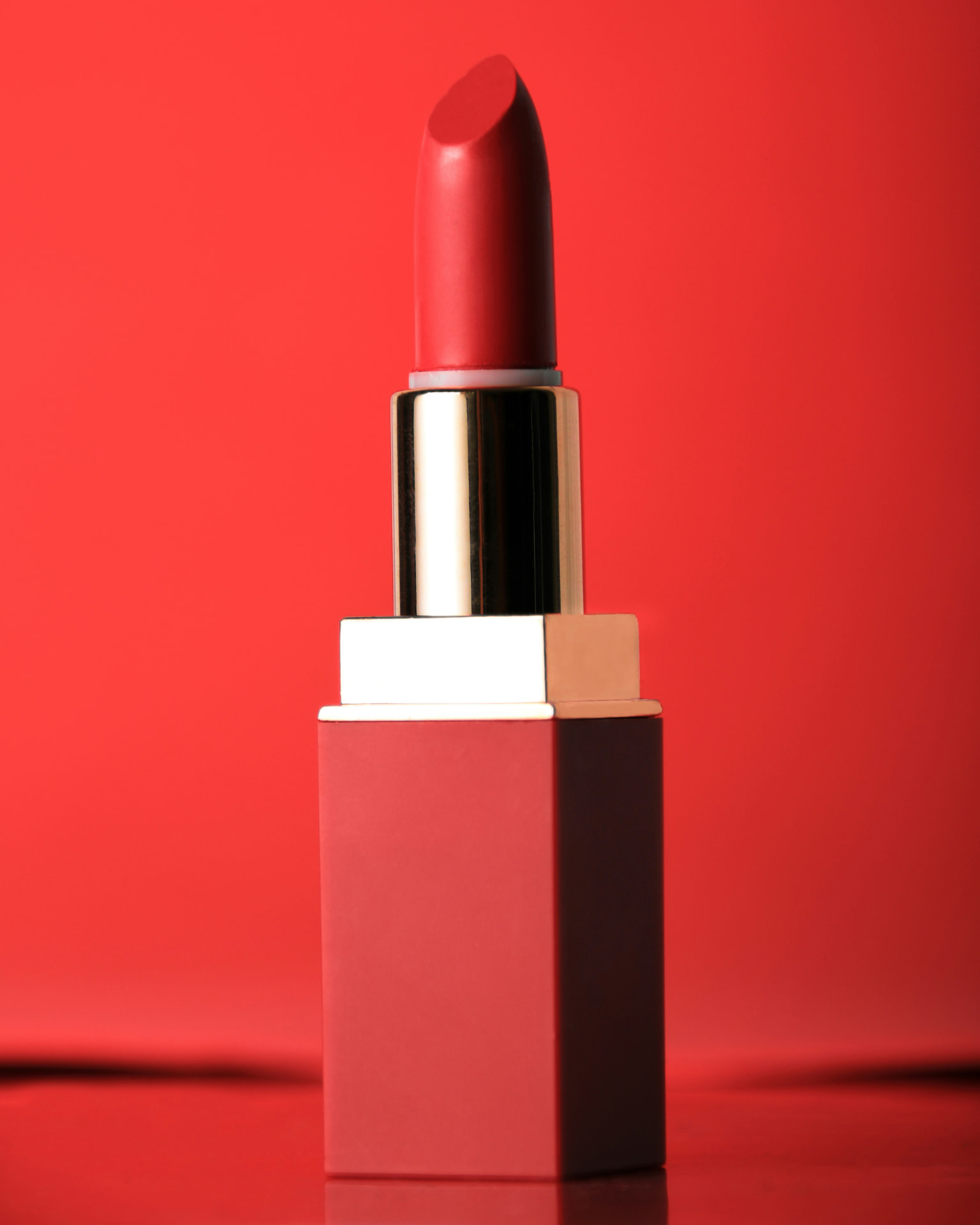 Rossetto rosso opaco con astuccio dorato su fondo rosso monocromatico