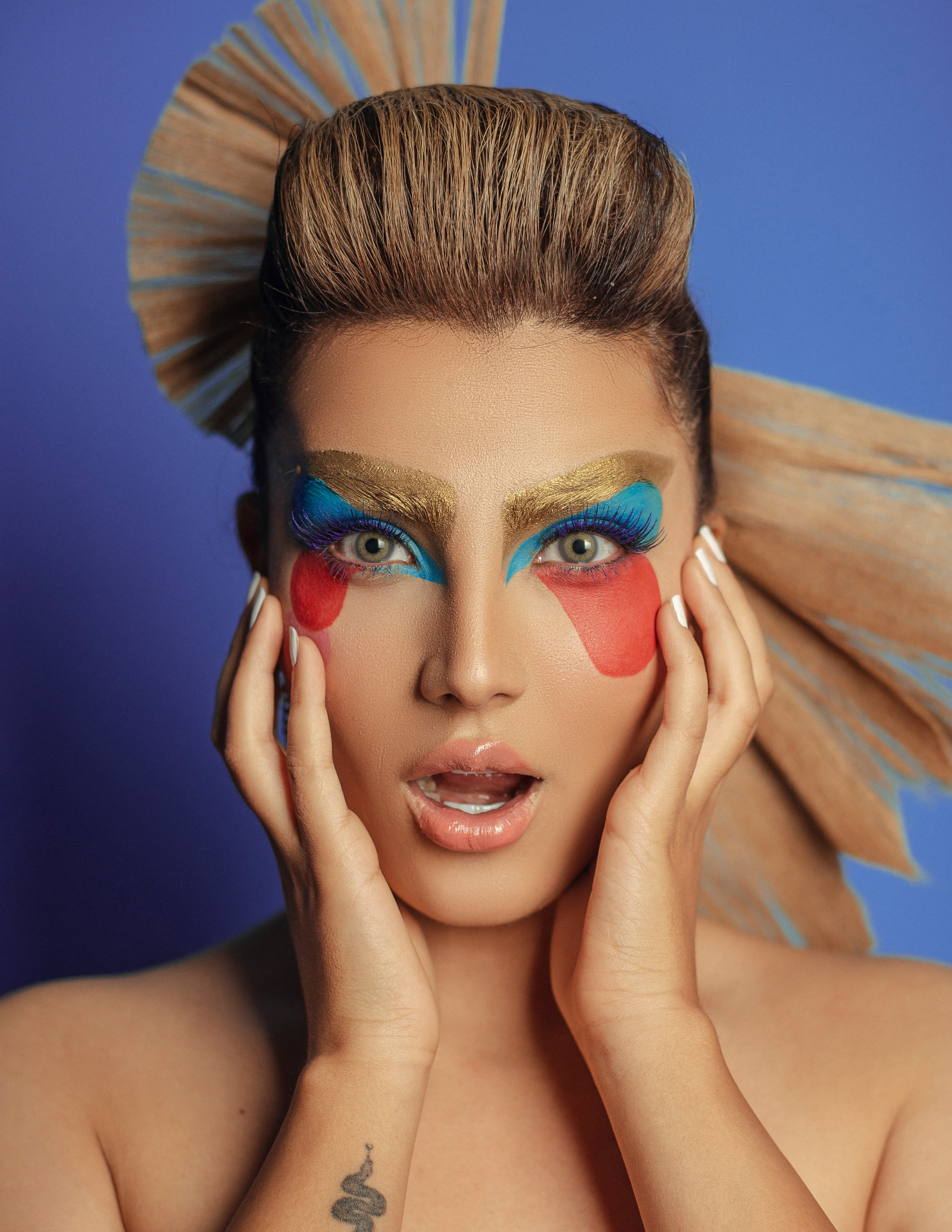 Trucco drag queen pop con sopracciglia dorate rialzate e blocchi di colore sugli occhi