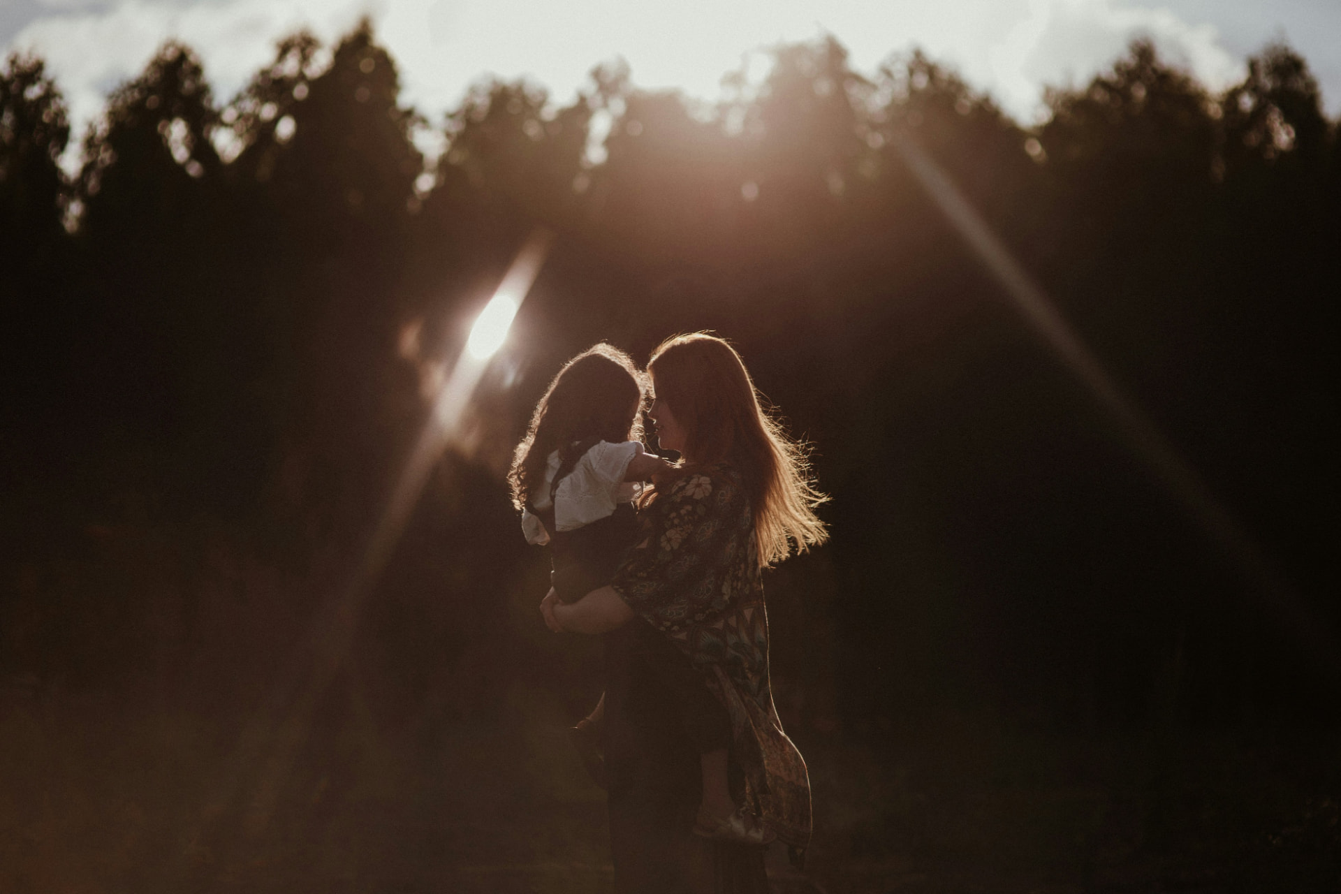 Mamma che abbraccia la figlia al tramonto