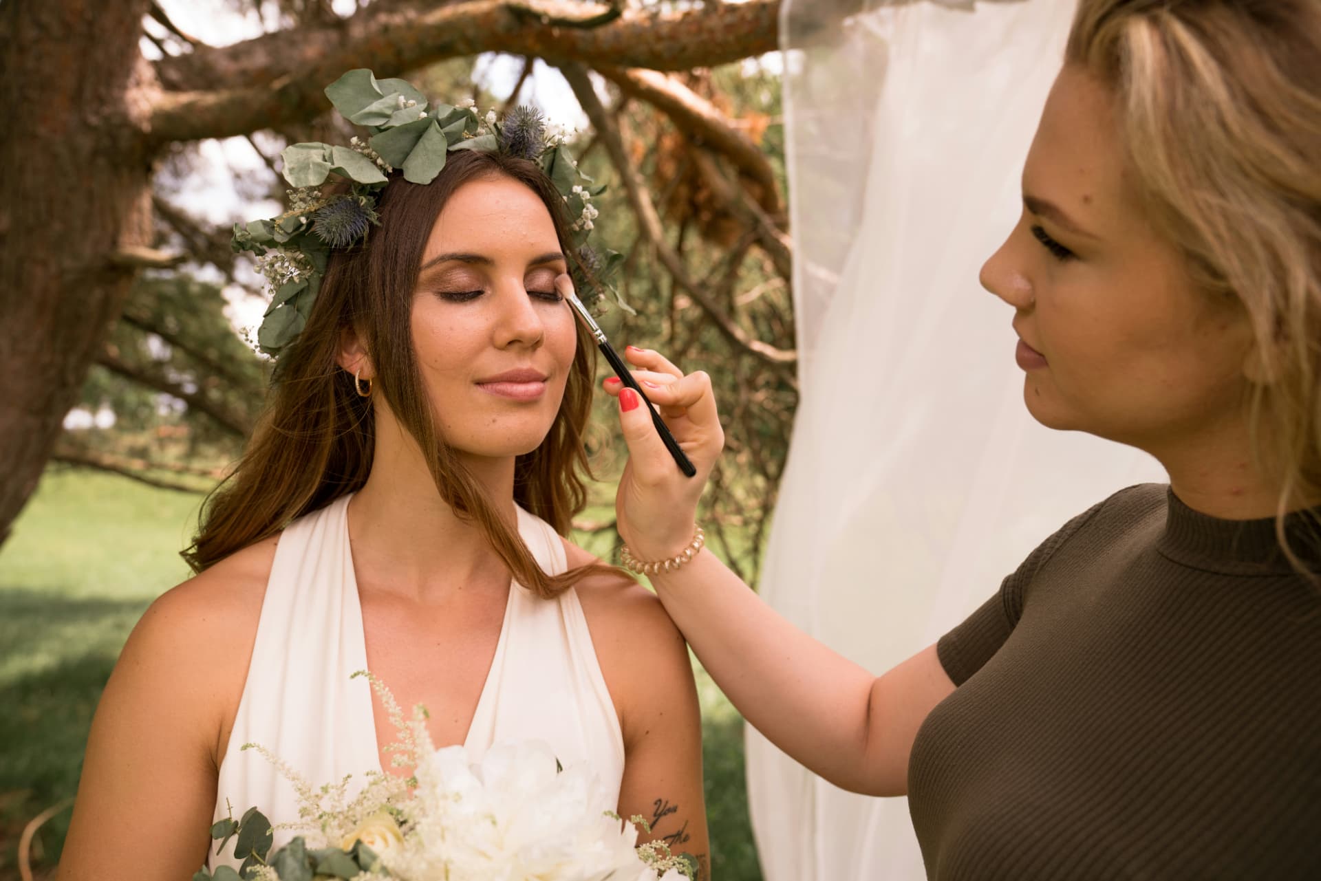 Trucco sposa: make-up artist applica ombretto alla sposa con corona di fiori